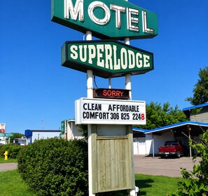 Un letrero de motel con la palabra 'MOTEL' y 'SUPERLODE' escrita, y un letrero que dice 'LO SENTIMOS' debajo.