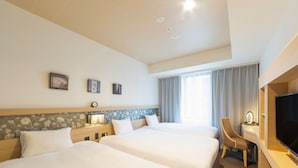 Een hotelkamer met twee bedden, een bureau met een televisie, een lamp en een raam met gordijnen.