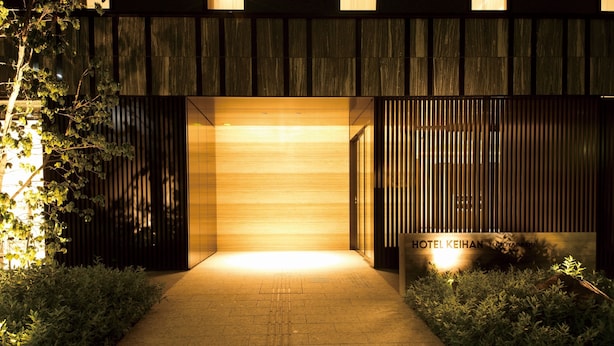 Een moderne hotelentree met een houten gevel, een bord waarop 