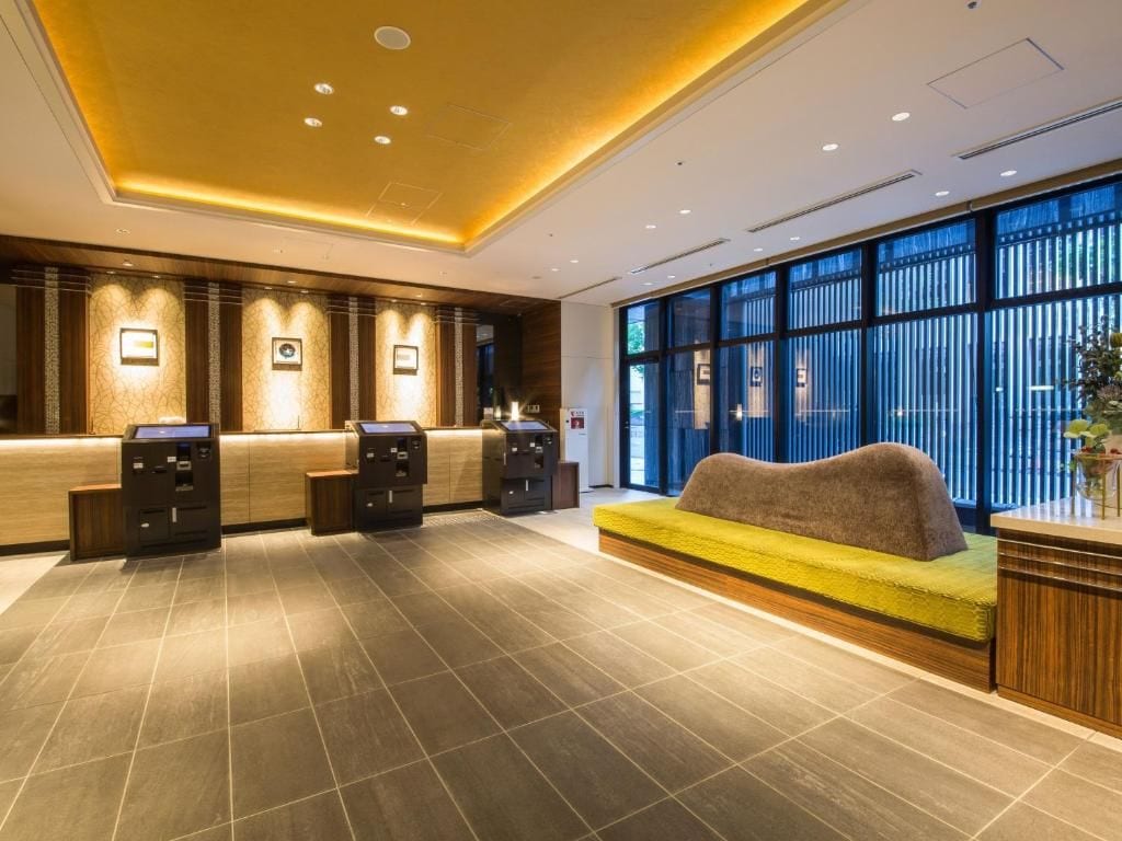 A reception area with a sofa, two reception desks, and a large window with blinds.