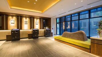 A reception area with a sofa, two reception desks, and a large window with blinds.