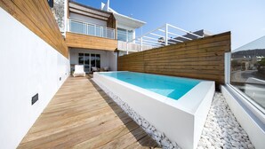 A modern outdoor swimming pool with a wooden deck and white pebbles, surrounded by a wooden fence and a white wall. - Hooope Inn (Checheng)