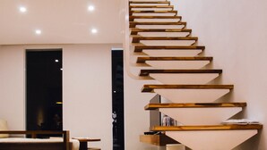 A modern staircase with wooden steps and white risers, leading to a dark doorway. - Hooope Inn (Checheng)