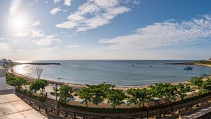 A coastal view with a beach, a pier, and a large building with a dome structure. - Hooope Inn (Checheng)