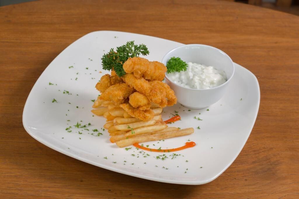 A plate of breaded and fried food, possibly chicken tenders, served with fries and a side of tartar sauce.
