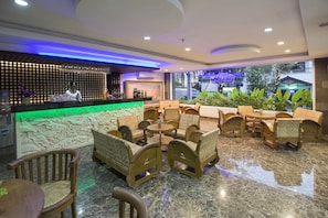 A lobby with a bar area, seating arrangements, and a view of the outside.