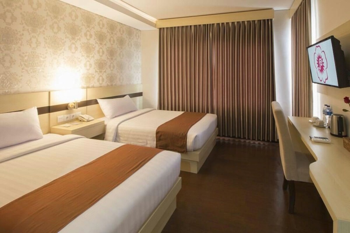 Een hotelkamer met twee bedden, een bureau, een stoel, een televisie en een raam met gordijnen.
