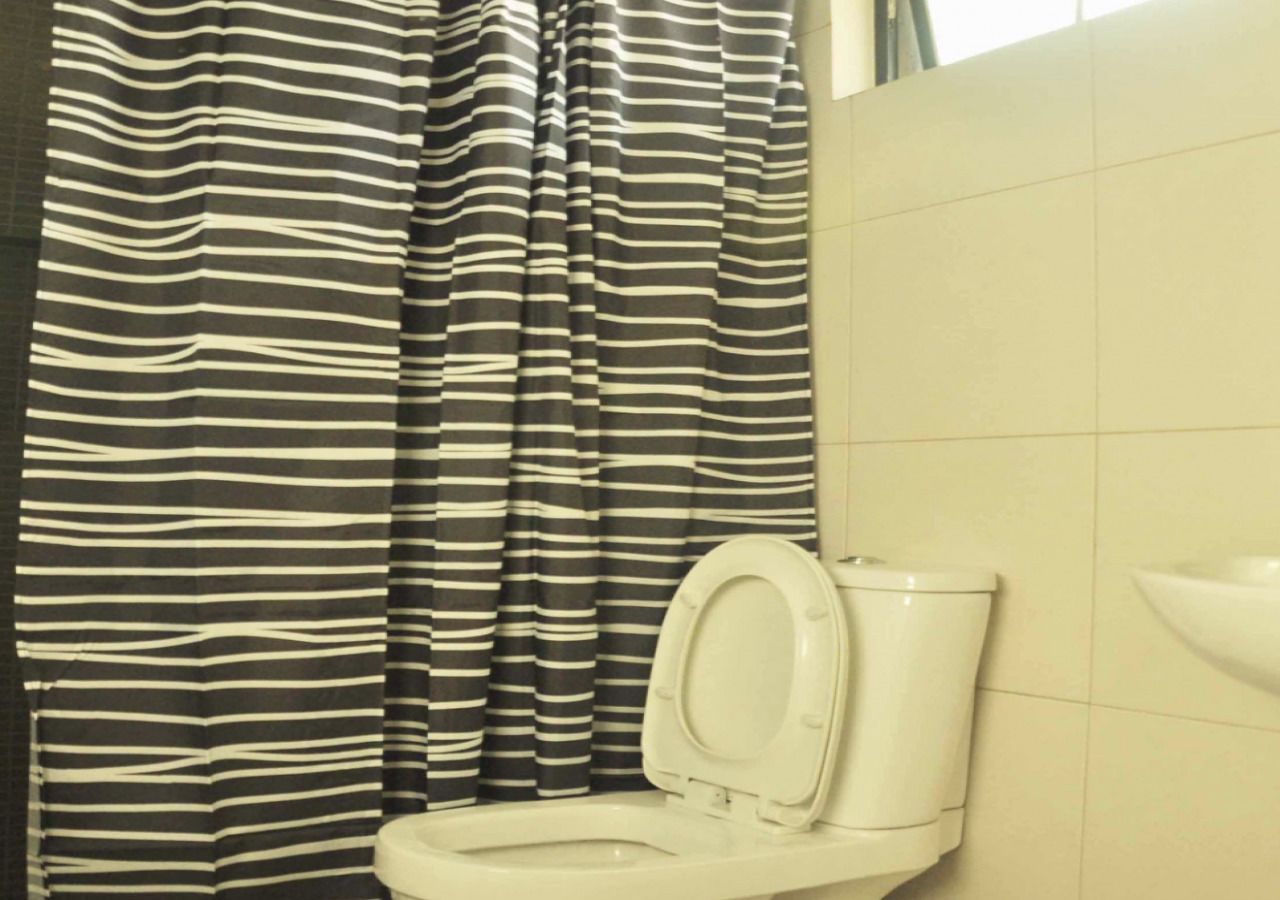 Une salle de bain avec un rideau de douche à rayures, des toilettes blanches et un lavabo avec un receveur.