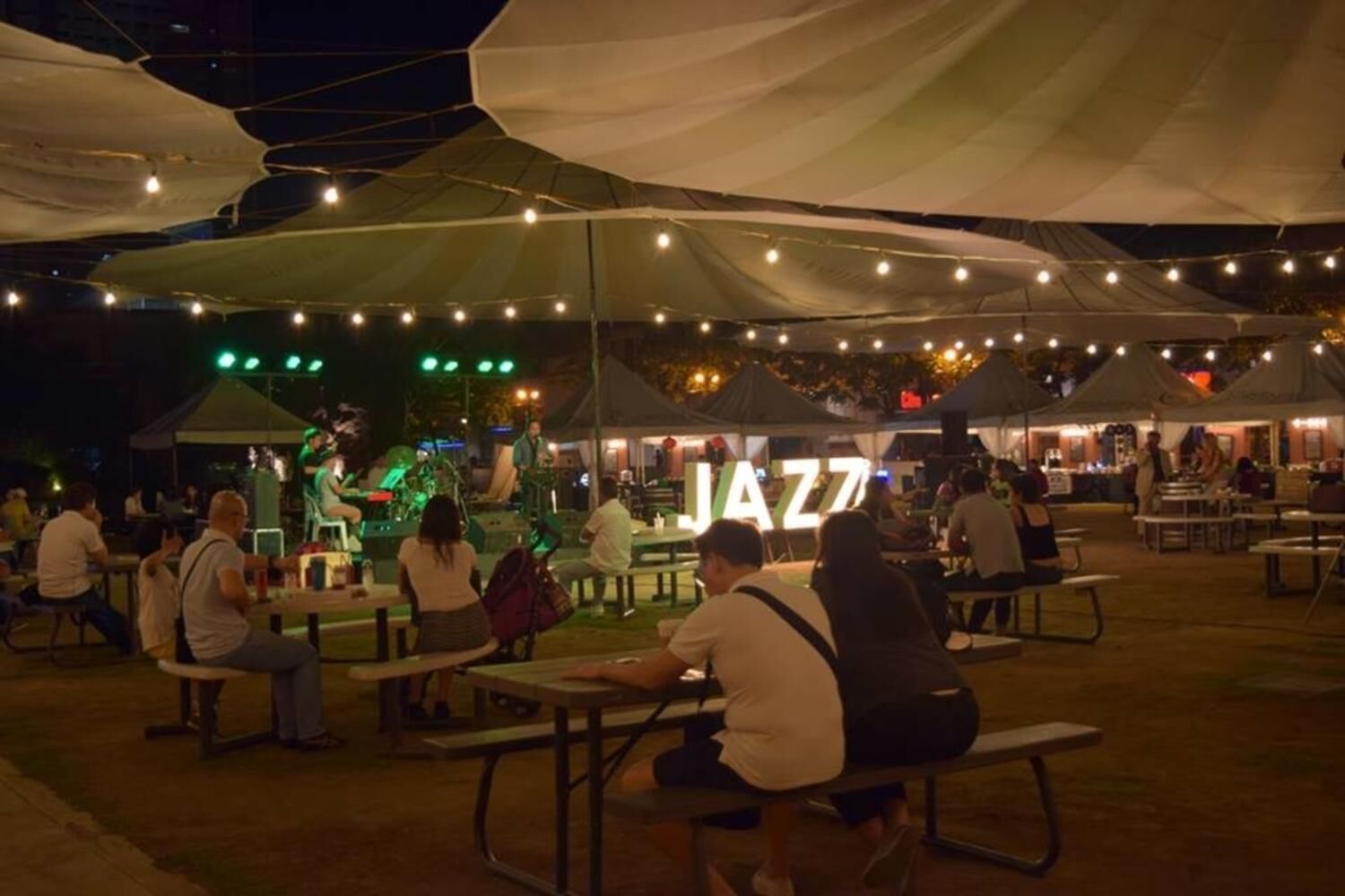 An outdoor dining area with tables and chairs under large tents.