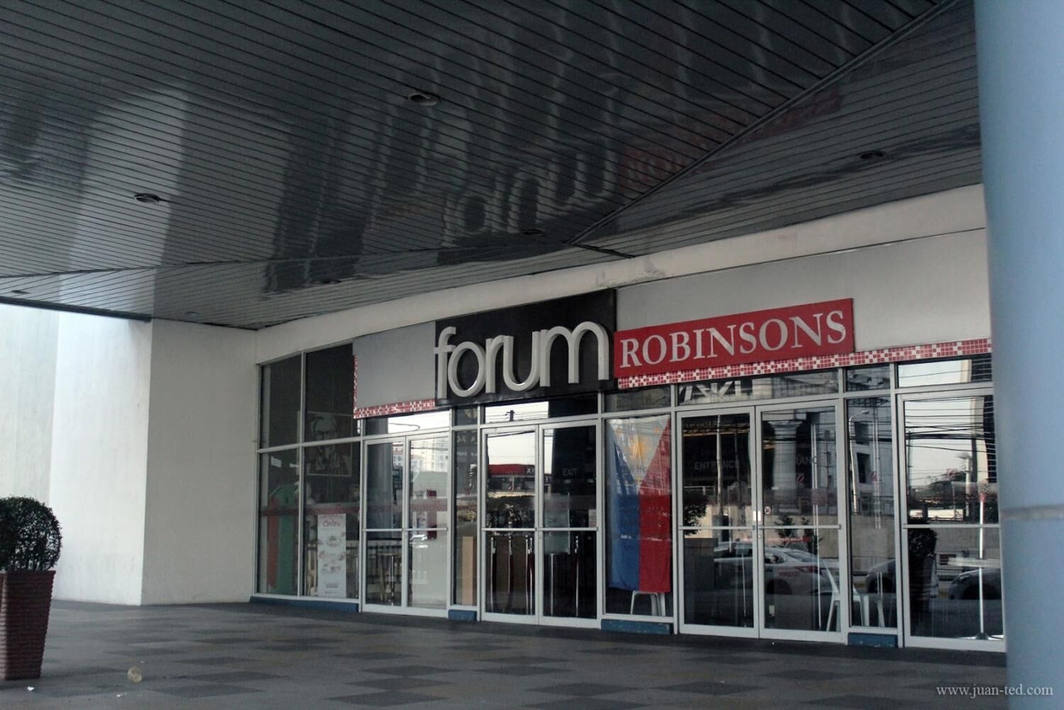 A building facade with 'forum' and 'Robinsons' signage, large glass windows, and a tiled entrance area.