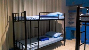 A bunk bed room with a blue mattress and pillows, a small desk with a chair, and a cabinet with blue doors. - Panglao Island Inn - Hostel (Panglao)