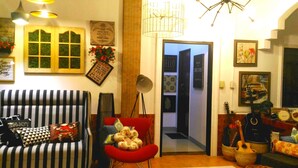 Una sala de estar acogedora con un sofá a rayas, un sillón rojo y una colección de guitarras.