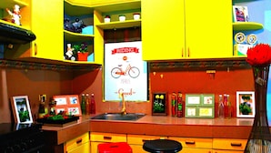 Una cocina con gabinetes amarillos, un taburete rojo y otro negro, y un letrero que dice 'Riding makes good'.