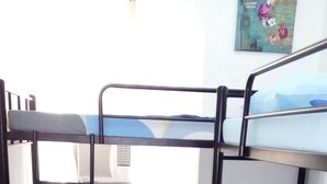 Habitación con literas, una ventana, un cuadro en la pared y piso de baldosas.