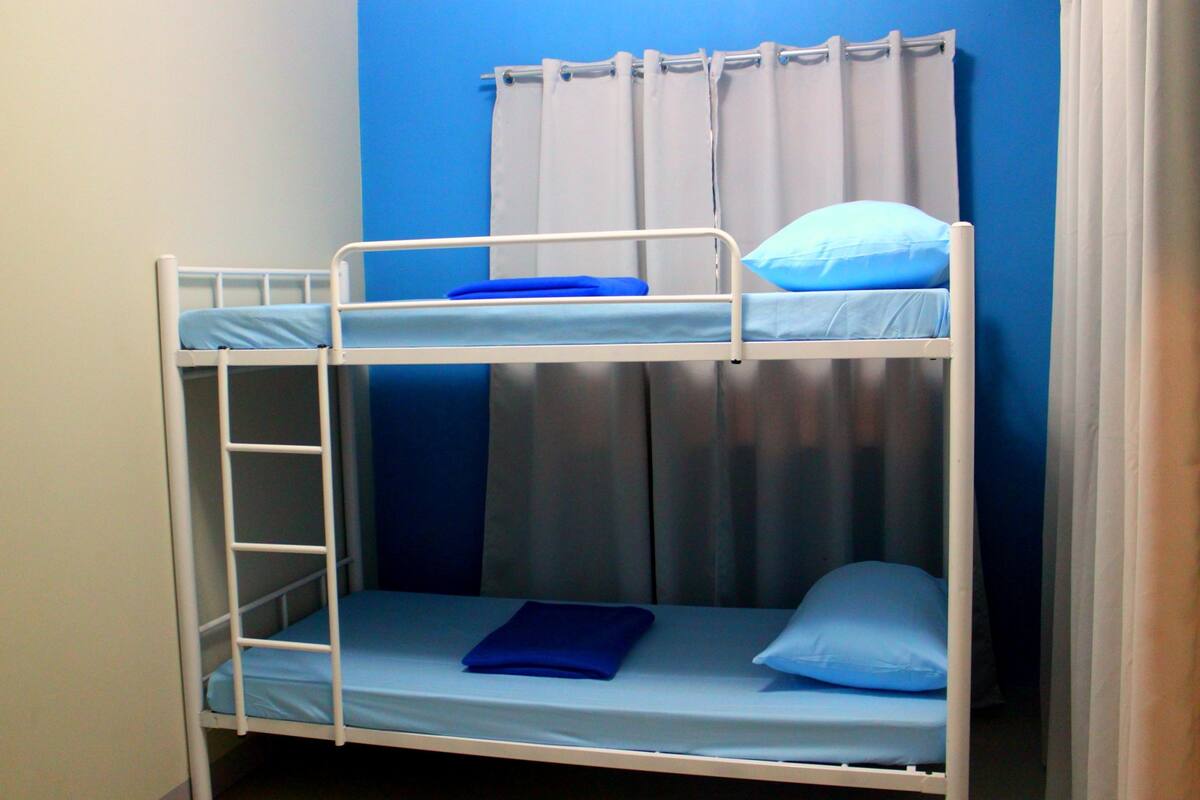 A bunk bed with a ladder, a blue mattress, and a pillow.
