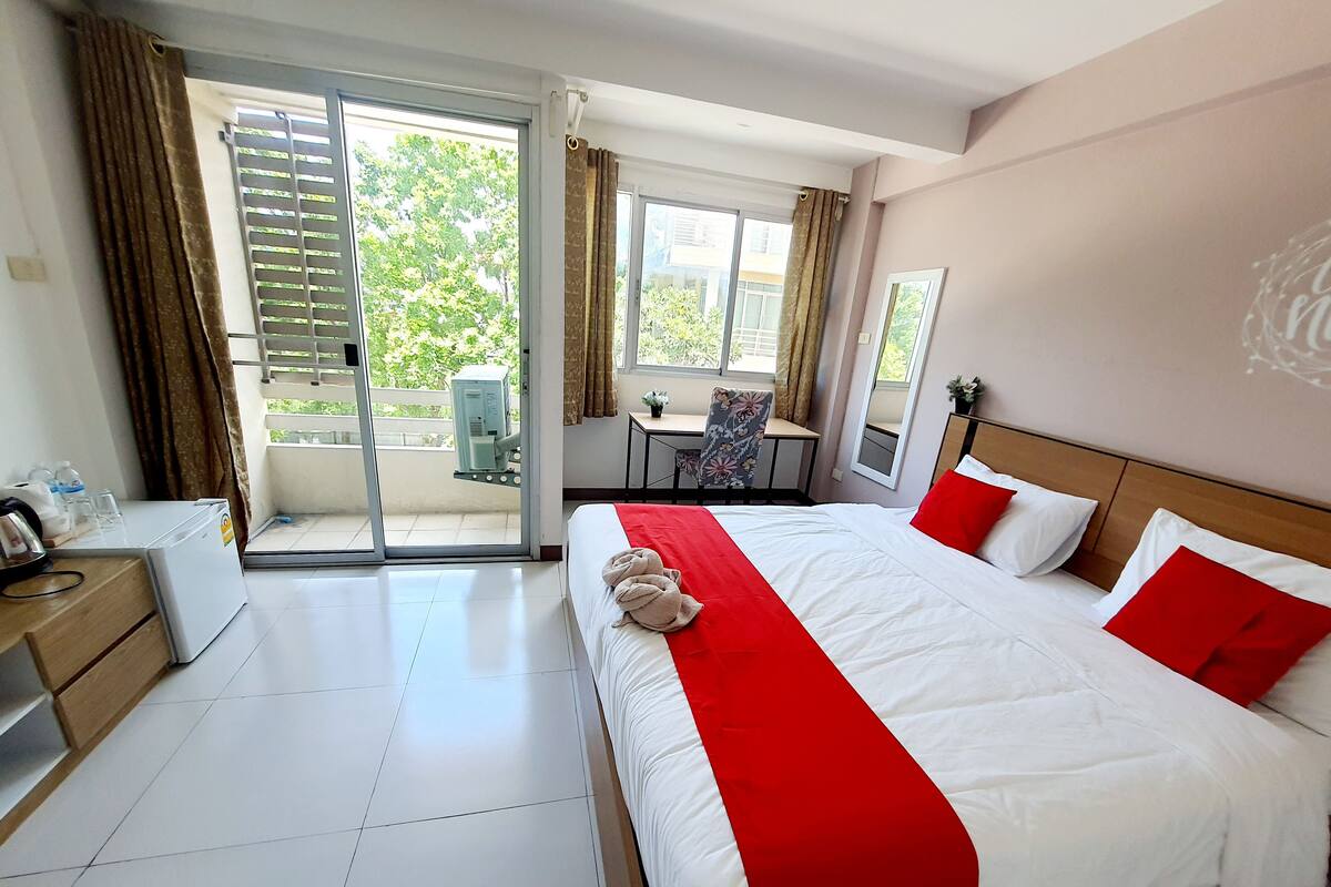 Een hotelkamer met een bed, een bureau, een stoel en uitzicht op de omgeving.