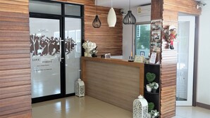 Un espace d’accueil doté d’un comptoir en bois, de deux lampes suspendues et d’une étagère murale agrémentée d’objets décoratifs.