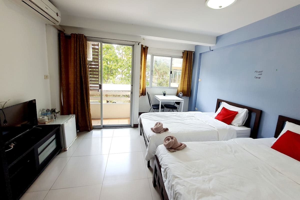 Een hotelkamer met twee bedden, een bureau, een stoel, een airconditioner en uitzicht op het omliggende landschap.