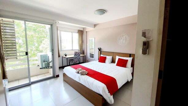 Une chambre moderne avec un grand lit, un bureau et une porte-fenêtre coulissante donnant sur un espace extérieur.