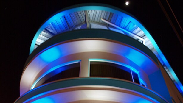 A multi-story building with a curved facade and illuminated blue lighting.