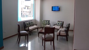 A modern living room with a large window, a flat-screen TV, and a unique blue ceiling light fixture.