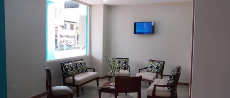 A modern living room with a large window, a flat-screen TV, and a unique blue ceiling light fixture.