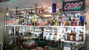 A bar area with shelves stocked with various liquor bottles and glasses. - Relax Time Silom - Hostel (Bangkok)