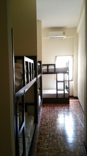 Una habitación con literas, una ventana con cortinas y un equipo de aire acondicionado en la pared.