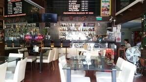 A bar area with a menu board, seating, and a counter with various items. - Relax Time Silom - Hostel (Bangkok)