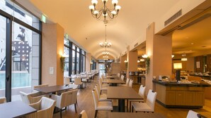 Un ampli restaurant amb sostres alts, lluminàries i grans finestrals que ofereixen vistes a la ciutat.