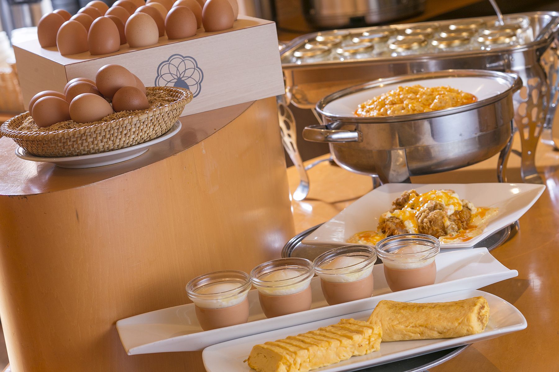 Een ontbijtbuffet met eieren, omeletten en diverse dranken.