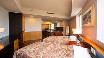 A hotel room with two beds, a desk with a chair, a television, and a mirror.