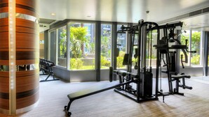 A gym with exercise equipment, large windows, and a wooden column.