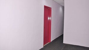 Un couloir aux murs blancs et à la porte rouge.