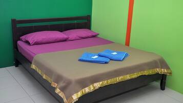 Ein Bett mit einer violett-braunen Tagesdecke, zwei blaue Handtücher und goldener Zierleiste.