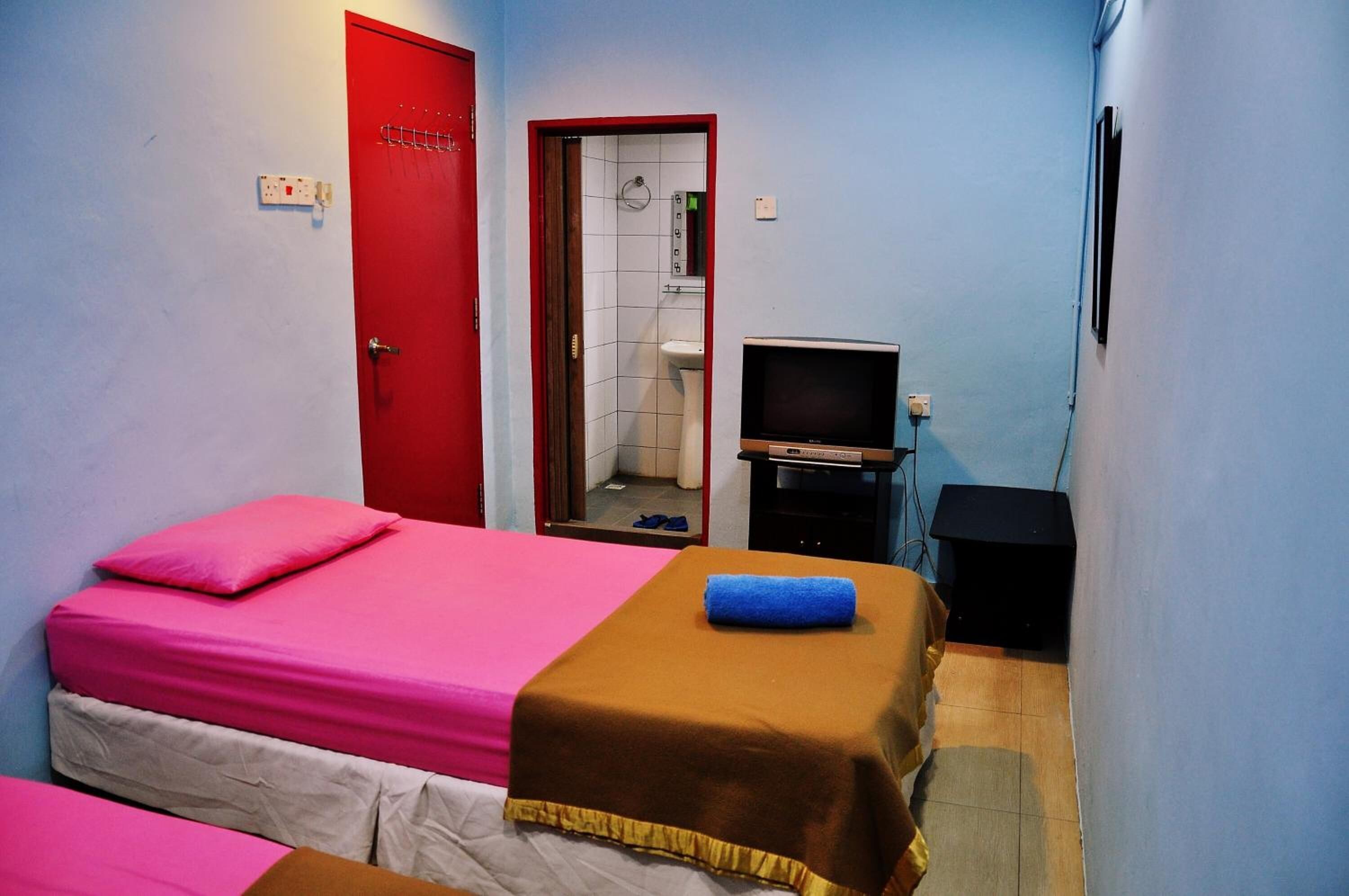 A small, compact room with a single bed, a television, and a bathroom visible through an open door.