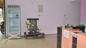 Un espace d’accueil comprenant un réfrigérateur de la marque 100 PLUS, un bassin décoratif avec des poissons et un panneau d’accueil.