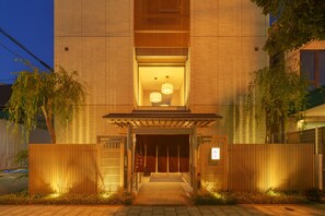 Un edificio moderno con fachada de madera, un acceso cubierto y un sendero que conduce a la puerta.