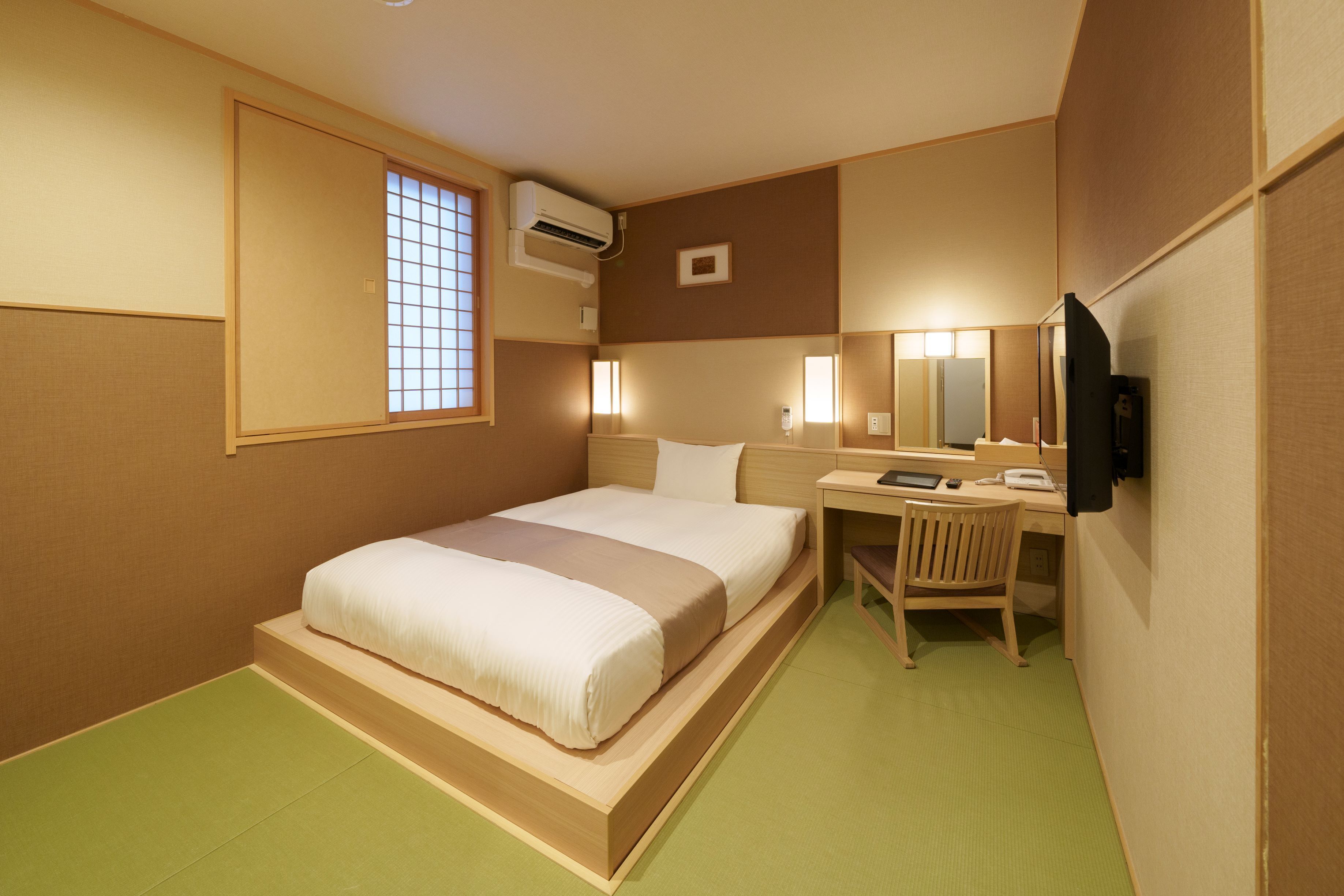 Una habitación de hotel con cama, escritorio, silla y televisión.