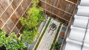 Ein kleiner, umzäunter Gartenbereich mit Kiesweg, verschiedenen Pflanzen und Holzzaun.