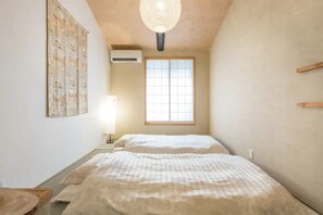 Ein Schlafzimmer mit zwei Betten, einem Fenster, einer Klimaanlage und einer Pendelleuchte.