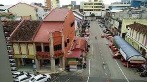 A street view with buildings, parked cars, and a bus. - Diyana Budget Hotel - Hostel (Kota Bharu)