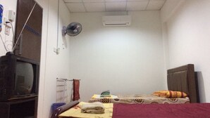 A small, simple room with a bed, a TV, a heater, and a wall-mounted fan. - Diyana Budget Hotel - Hostel (Kota Bharu)