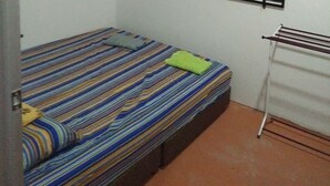 A small, single-bed room with a striped bedspread, a window with metal bars, and a drying rack against the wall. - Diyana Budget Hotel - Hostel (Kota Bharu)