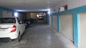 Eine Parkgarage mit einem weißen Auto und abgestellten Motorrädern. Die Wände sind blau und weiß gestrichen, der Boden besteht aus Beton.