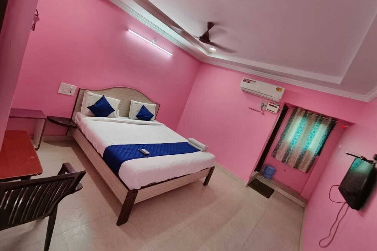 A pink-themed room with a bed, a desk, and a chair.