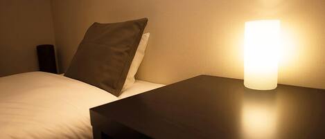 Una cama individual con una almohada y una mesita de noche con lámpara.