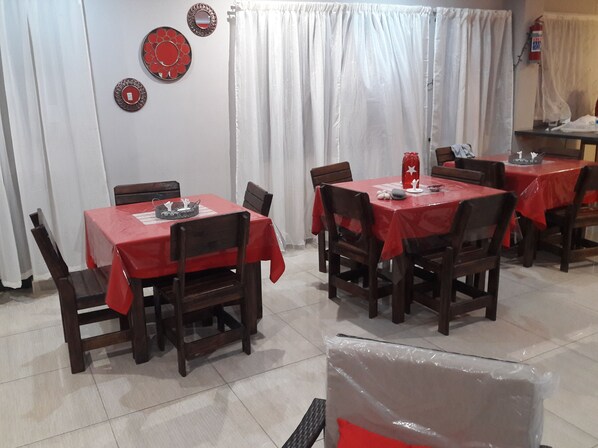 A dining area with tables covered in red tablecloths, wooden chairs, and decorative wall mirrors.