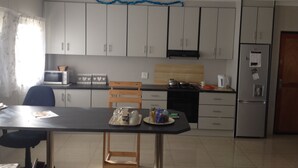A kitchen with white cabinets, a microwave, a stove, and a refrigerator. - Jessma Bed and Breakfast (Walvis Bay)