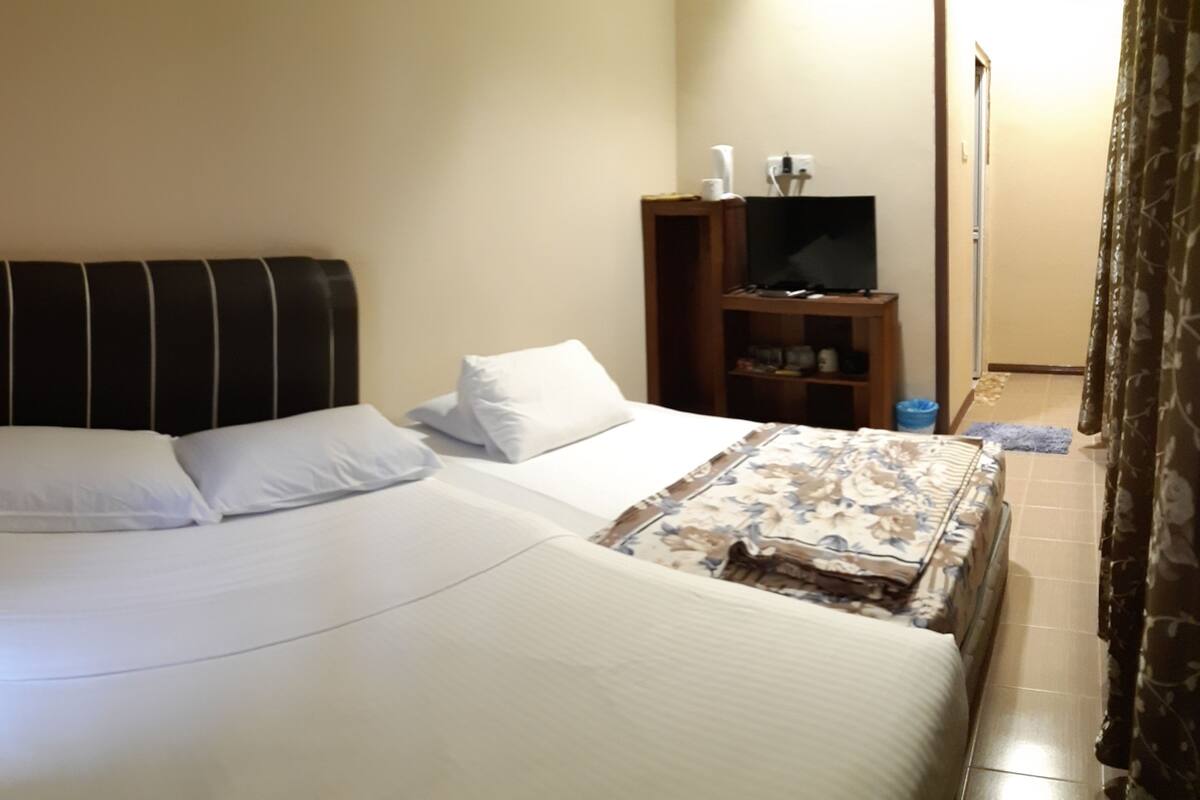 A neatly made bed with white linens and a floral-patterned throw.